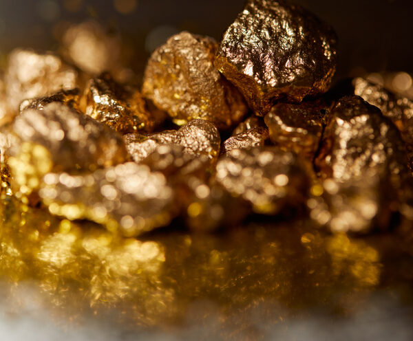 selective focus of golden stones on dark sparkling surface and black background